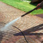 Cleaning street with high pressure power washer, washing stone garden paths